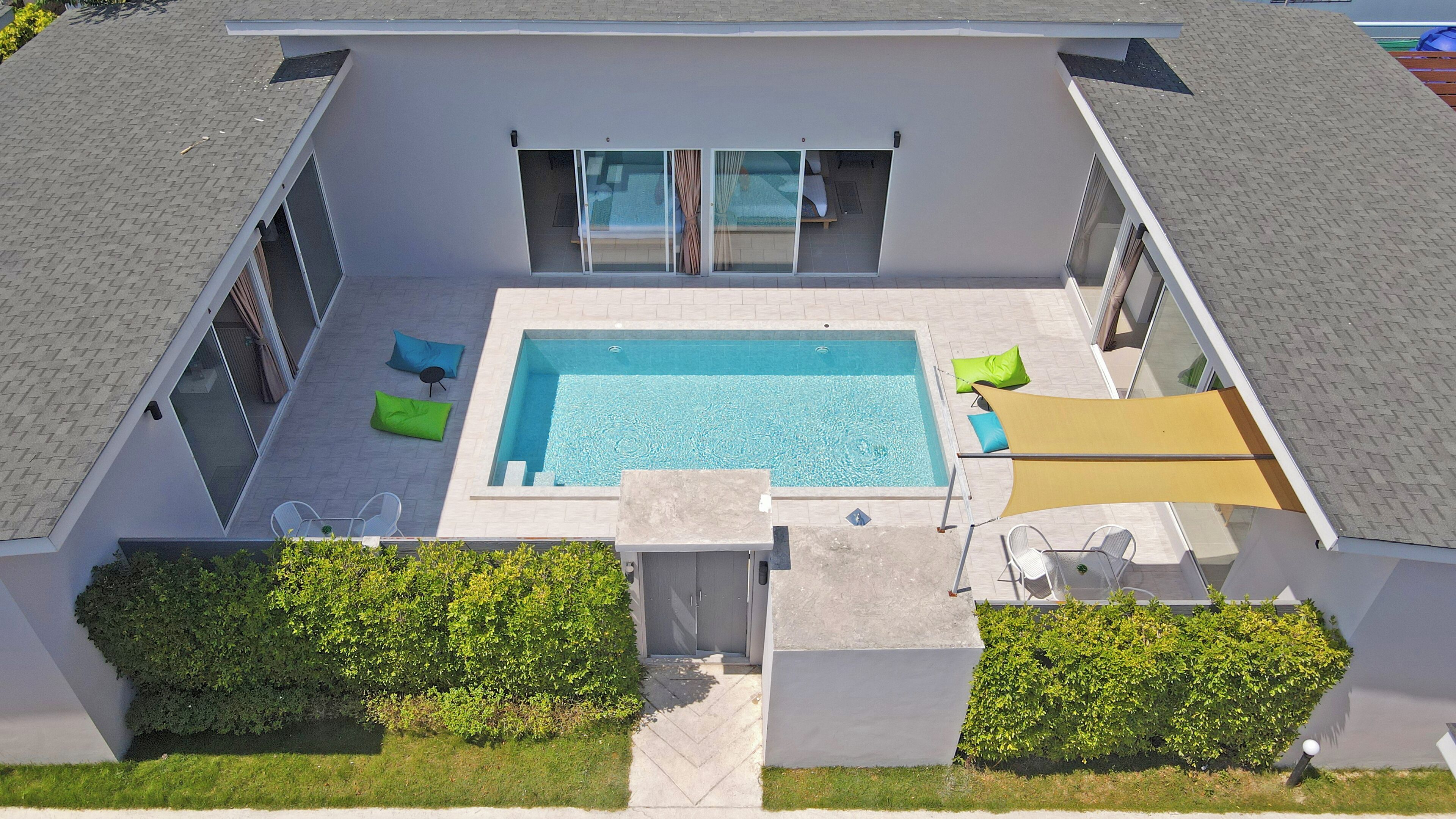 A modern house with a swimming pool, outdoor seating, and a covered patio area.
