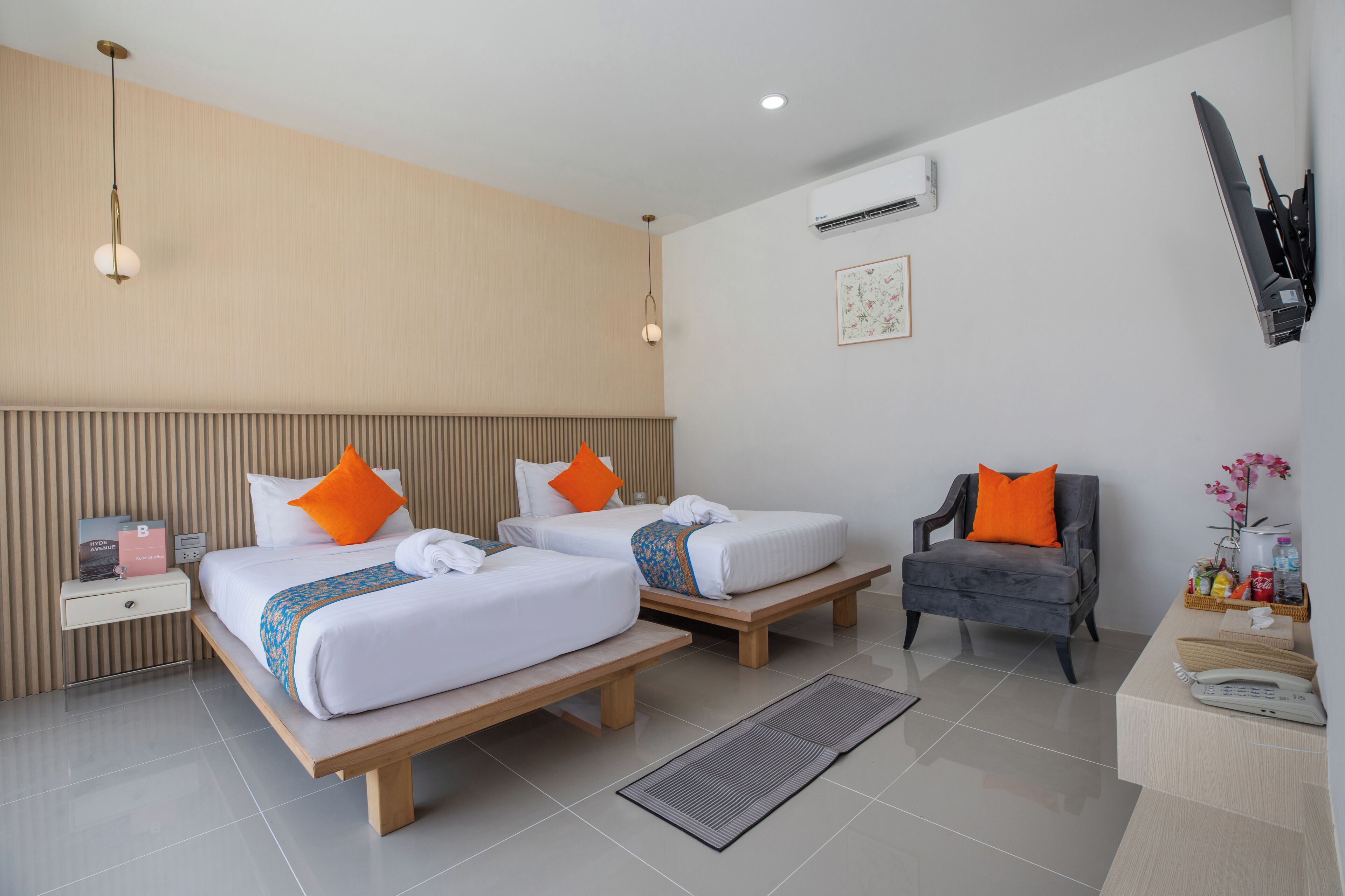 A hotel room with two beds, a chair, a desk, a nightstand, and a wall-mounted TV.