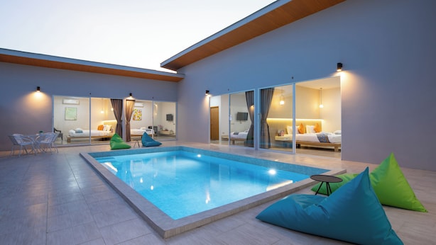 A modern indoor pool area with a clear pool, seating, and a view into the adjacent bedroom. - Andaman Sea Best Pool Access & Villas   (Chalong)
