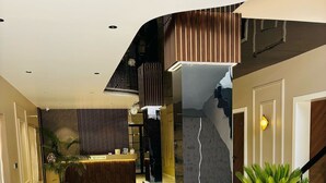 A spacious lobby with a reception desk, a staircase, and a potted plant. - Hotel Meritus Mount Abu (Abu Road)
