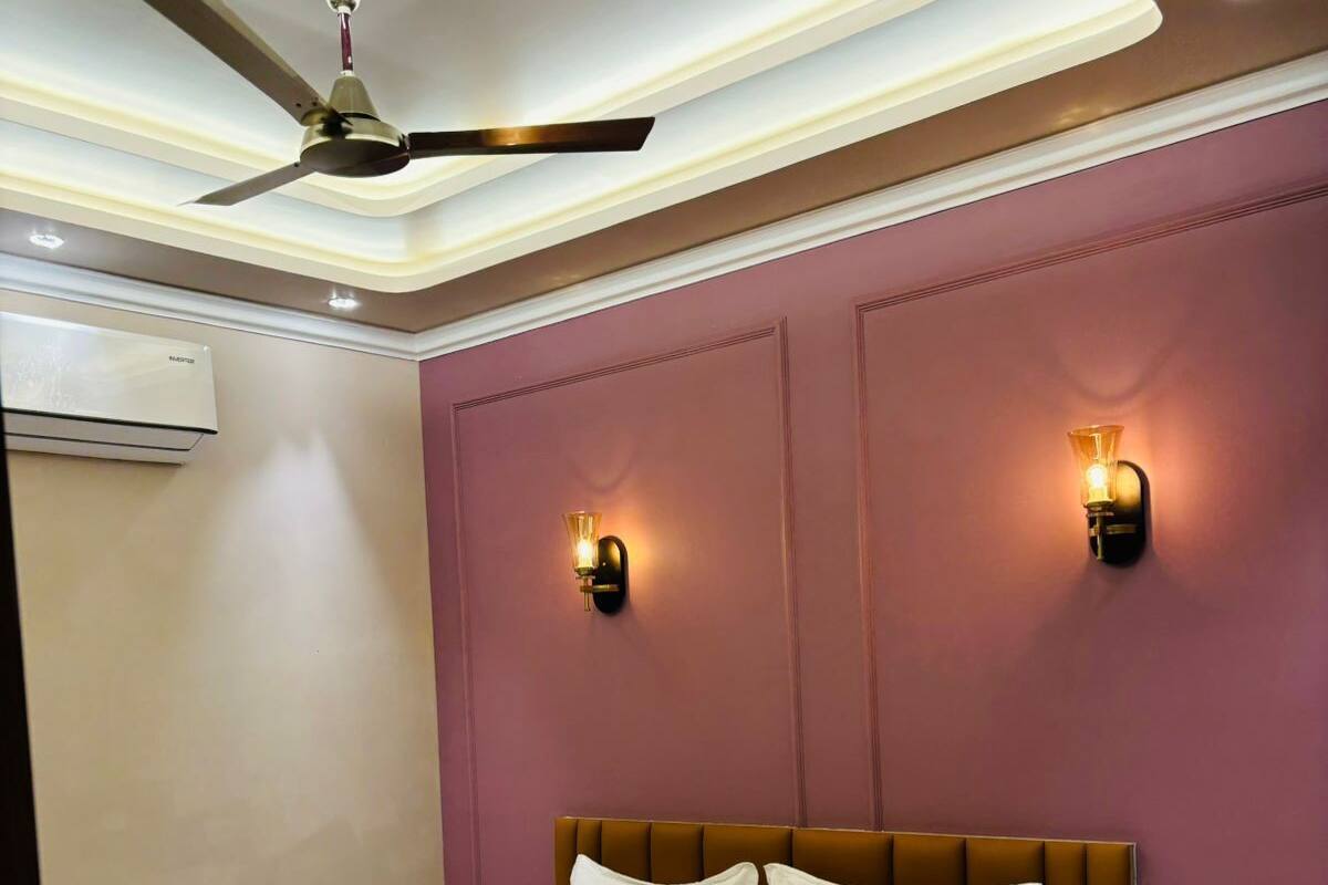 Una habitación de hotel moderna con una cama grande, ventilador de techo, luces fijadas en la pared y equipo de aire acondicionado.
