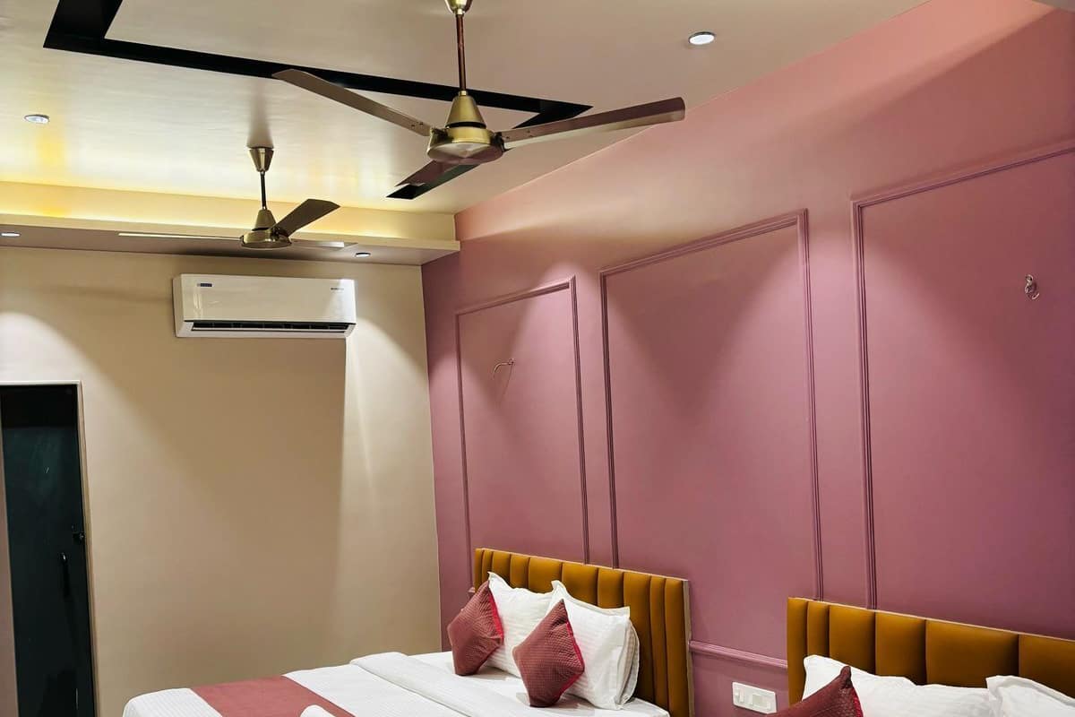 Habitación de hotel con dos camas, ventilador de techo, equipo de aire acondicionado y suelo de mármol.