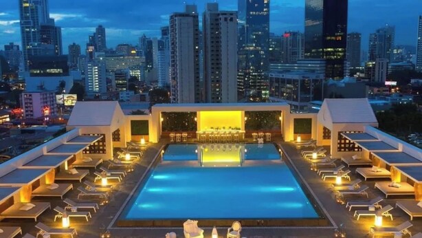 A rooftop pool with lounge chairs and a bar area, surrounded by high-rise buildings. - Exclusive and luxury 1BR with balcony in Yoo Panama (Panamá)