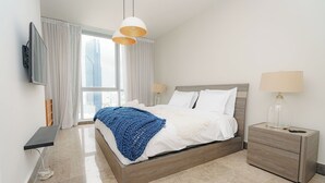 A modern bedroom with a bed, bedside tables, a TV, and a view of the city. - Exclusive and luxury 1BR with balcony in Yoo Panama (Panamá)