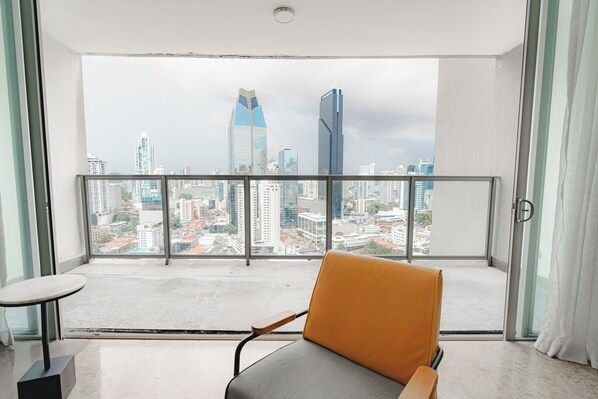 Un balcón con vistas a un paisaje urbano, una silla y una mesita.