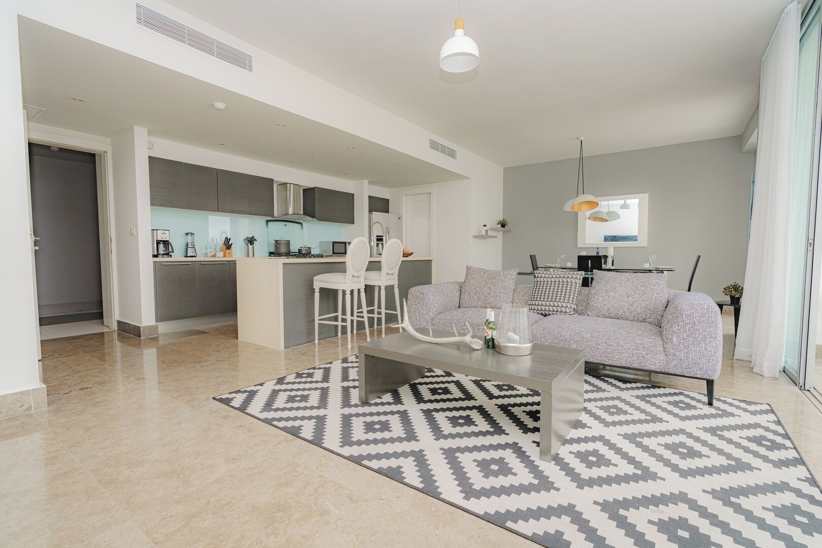 Una sala de estar moderna con un sofá gris, una mesa de centro y una alfombra estampada.