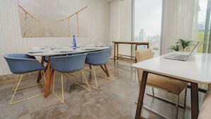 Un comedor moderno con una mesa grande, sillas azules y un ordenador portátil sobre una mesita auxiliar.