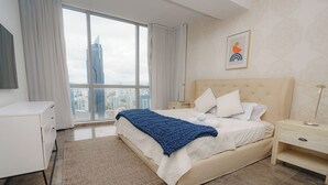 Un dormitorio moderno con una cama grande, una mesita de noche, un escritorio y vistas a la silueta urbana.