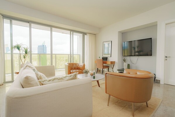 A modern living room with a sofa, armchairs, a dining table, and a TV.