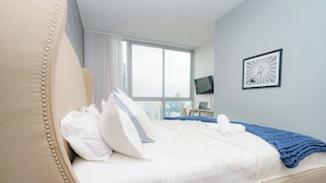 Ein Hotelzimmer mit Bett, Fernseher und Fenster mit Blick auf die Stadt.