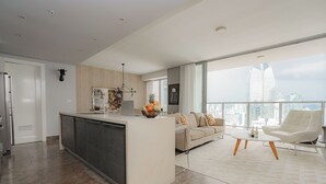 A modern apartment with a kitchen island, a sofa, a coffee table, and a city view.