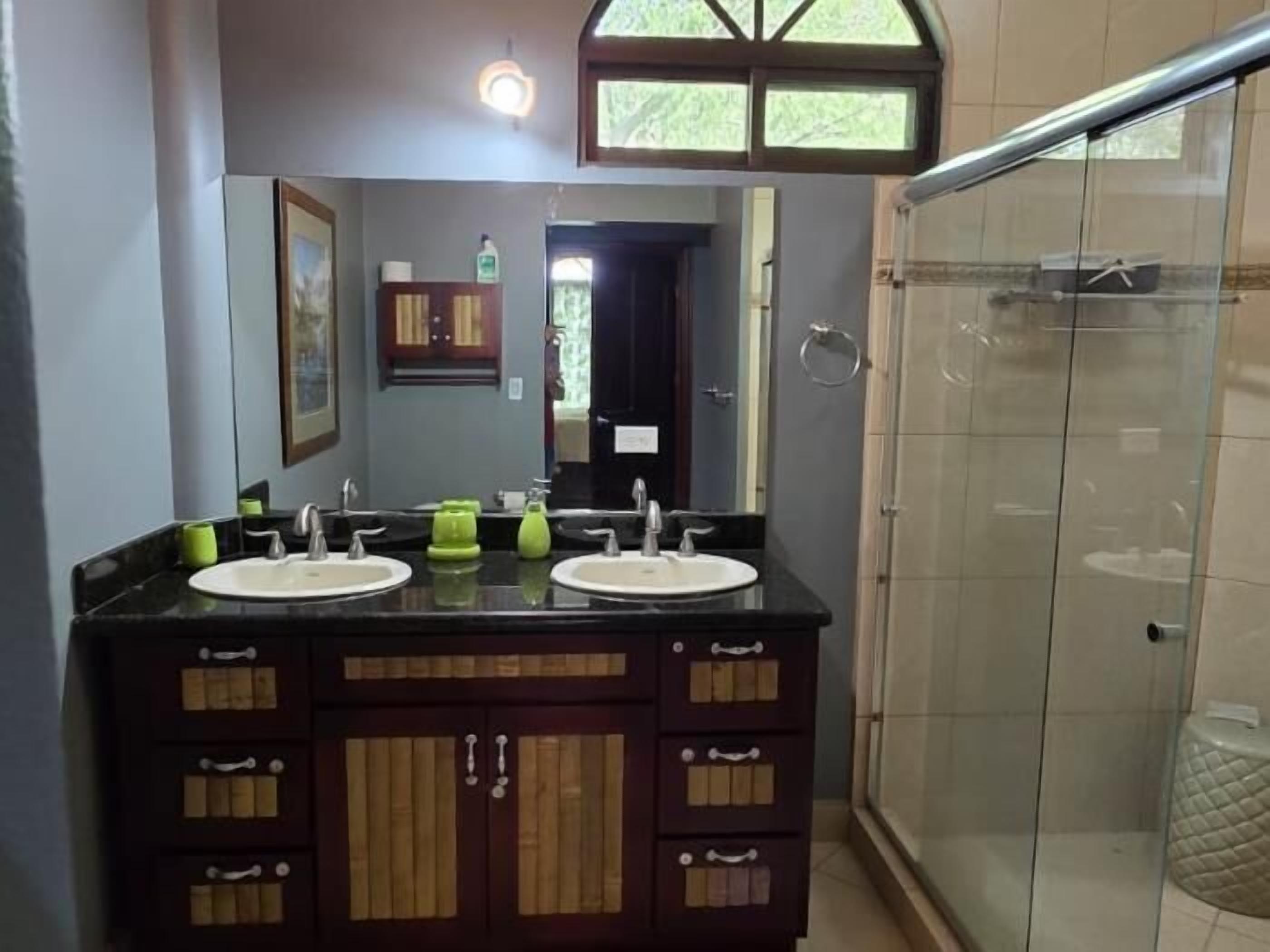 Une salle de bain avec deux lavabos, un miroir et une douche en verre.