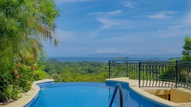 Une piscine offrant une vue sur l’océan et entourée d’une végétation luxuriante.
