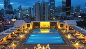 A rooftop pool with lounge chairs and a bar area, surrounded by high-rise buildings. - Exclusive and luxury 1BR with balcony in Yoo Panama (Panamá)