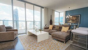 A spacious living room with a large window, a white coffee table, and a sofa set.