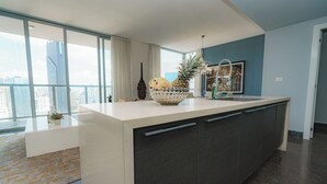 A modern kitchen with a large island, a view of the city, and a blue accent wall.