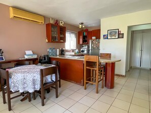 A compact kitchen with a dining area, featuring a built-in microwave, refrigerator, and a small island with a sink.