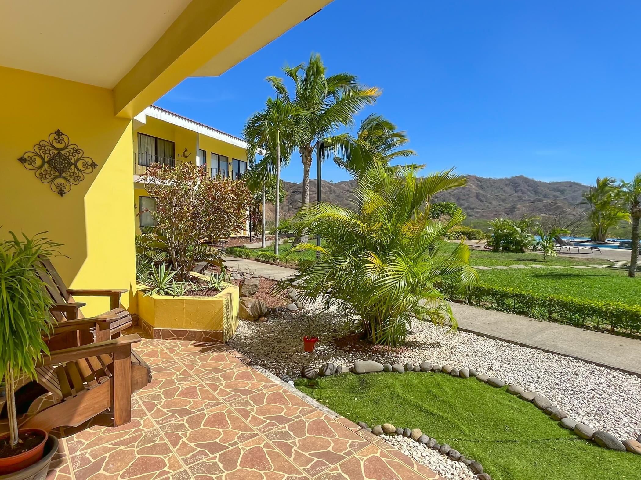 A yellow building with a patio area, outdoor seating, and a view of a mountain range.