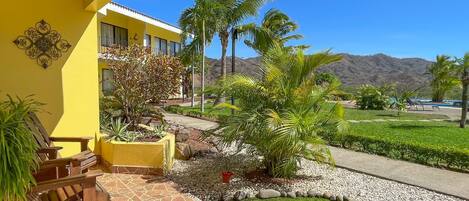 A yellow building with a patio area, outdoor seating, and a view of a mountain range.