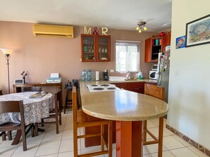 A kitchen with a central island, wooden cabinets, a refrigerator, and a dining area with a table and chairs.