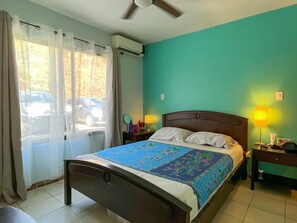 Ein Hotelzimmer mit einem Bett, zwei Nachttischlampen, einem Deckenventilator und einem Fenster mit Vorhängen.