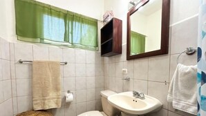 A bathroom with a toilet, sink, and green window.