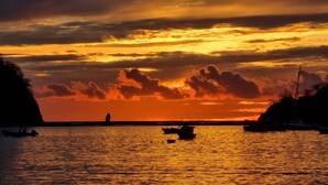 A sunset over a calm sea with boats and a rocky coastline. - Colinas Turquesa L4C Spectacular Ocean-View Vacation Rental (Playas del Coco)