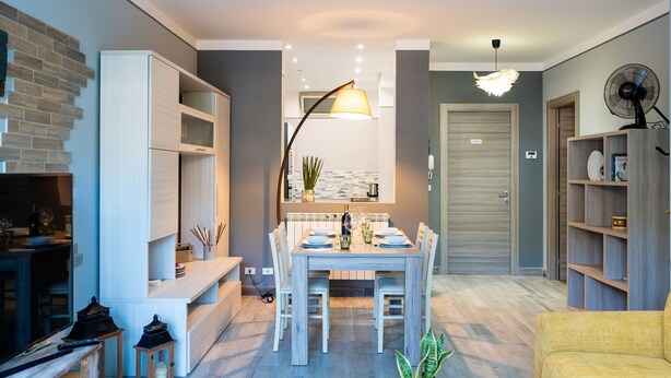 Un salon moderne avec un coin repas, des meubles en bois et un ventilateur.