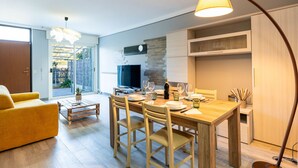 Un salon moderne avec un coin repas, un téléviseur et une grande fenêtre.