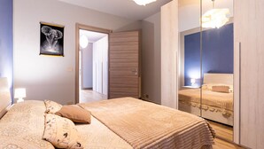 Une chambre à coucher avec un grand lit, une armoire, un miroir et un tableau encadré au mur.