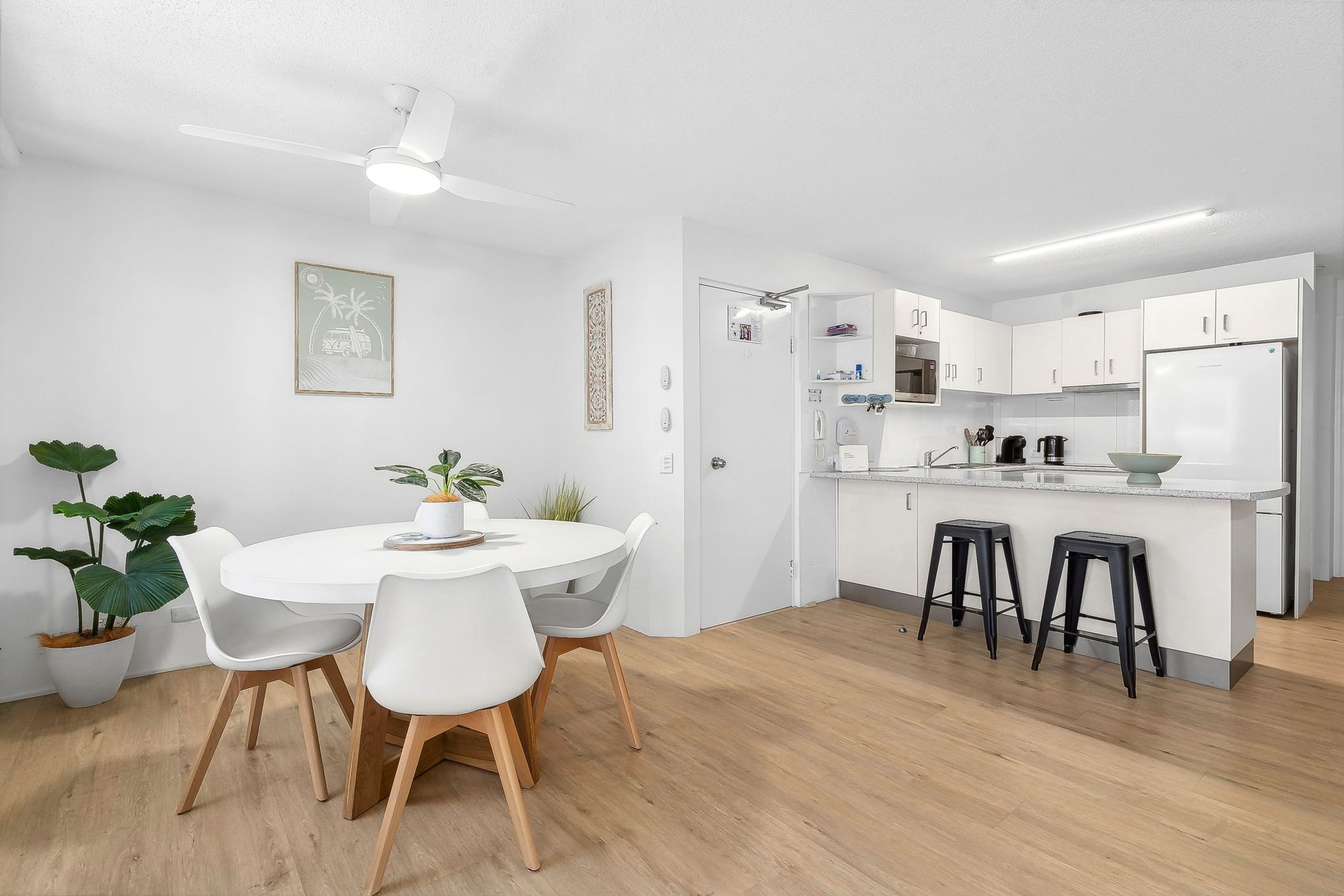 A modern kitchen with white cabinets, a microwave, and a refrigerator.