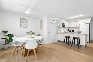 A modern kitchen with white cabinets, a microwave, and a refrigerator. - Cheltenham 4 - Kings Beach Escape With Ocean Views (Caloundra)