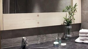 A modern bathroom with a large mirror, a round sink, and a potted plant. - Hôtel Le Ski d'Or (Tignes)