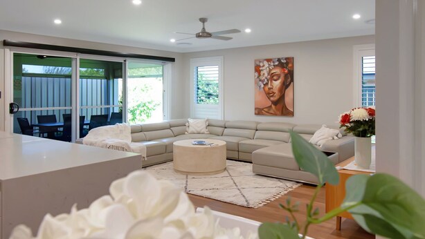 A modern living room with a sofa, coffee table, and a dining area with chairs.
