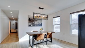 Et moderne spiseområde med et træbord, to stole og en hængende lampe.