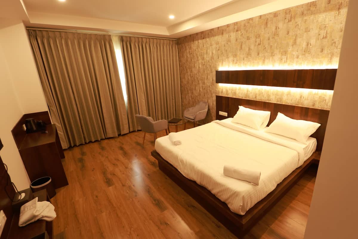A hotel room with a large bed, a desk with a chair, a small table, and a sofa.