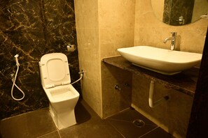 A bathroom with a toilet, sink, and mirror. - Hotel Dwaraka (Bengaluru)
