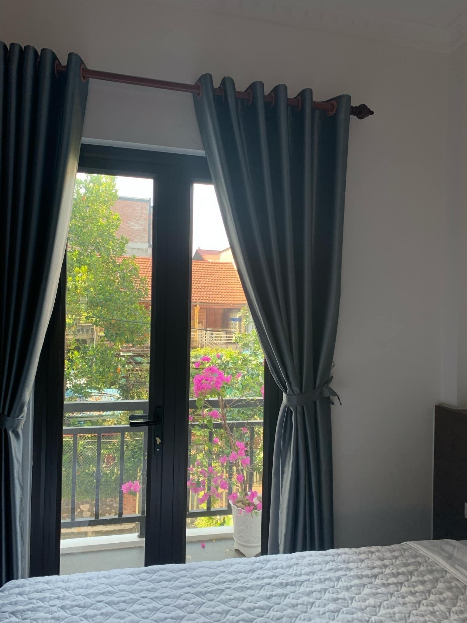Una habitación con cama, un balcón con barandilla y cortinas.
