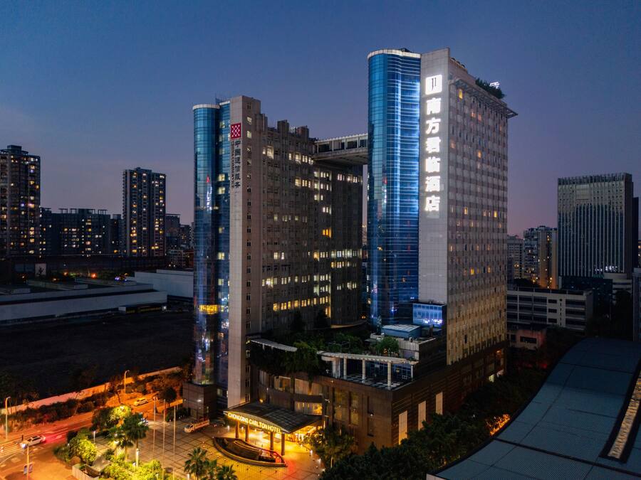 Un hotel de diseño moderno, con una fachada de vidrio curva destacada y un jardín en la azotea.