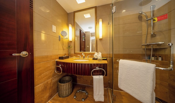 Een moderne badkamer met een houten wastafelmeubel, een douchecabine met glazen wanden en een grote spiegel.