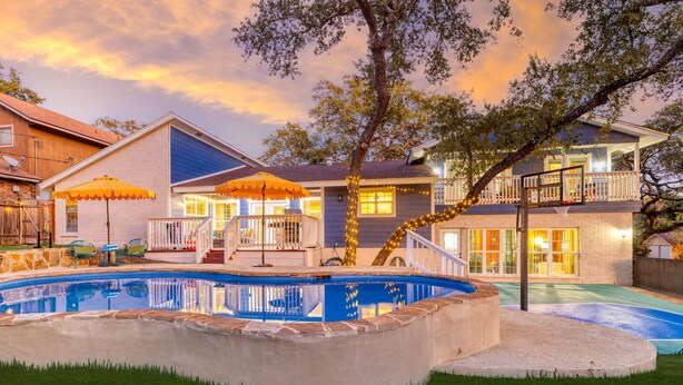 A backyard with a swimming pool, a basketball court, and a covered patio area. - The Sunburst: Sleeps 18! Basketball & Heated Pool (San Antonio)