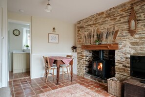 A cozy room with a stone fireplace, a dining table with chairs, and a television.