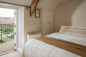 A bedroom with a bed, a radiator, a door leading to a balcony, and a framed picture on the wall.
