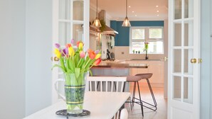 A modern kitchen with a central island, pendant lighting, and a view into the dining area. - Princes Esplanade (Gurnard)