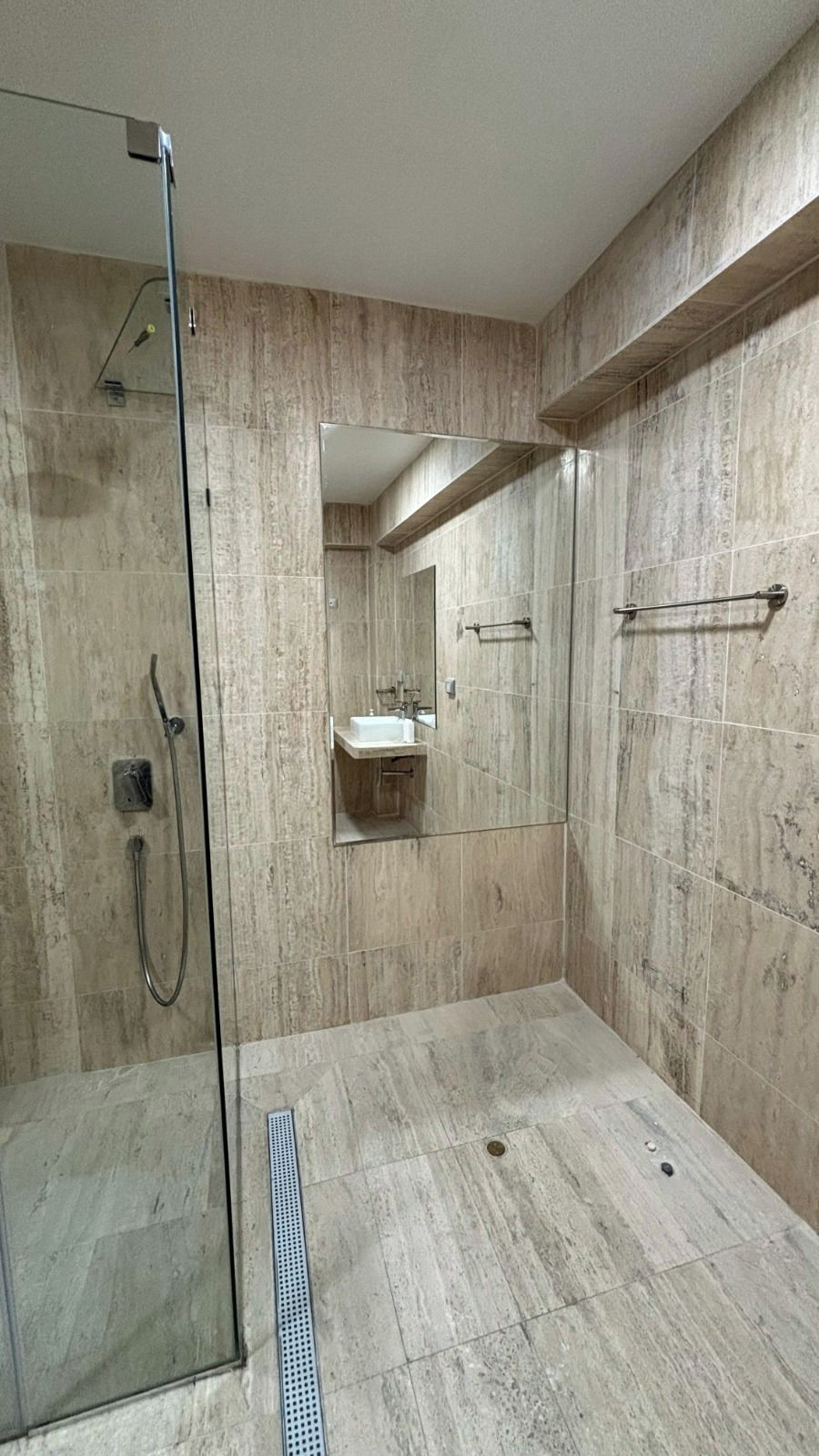 A modern bathroom with a glass shower enclosure, a sink, and a mirror.