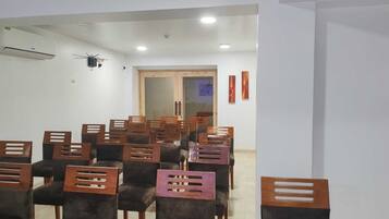 Una sala de conferències amb files de cadires, un aire condicionat i una porta que dona a una altra sala.