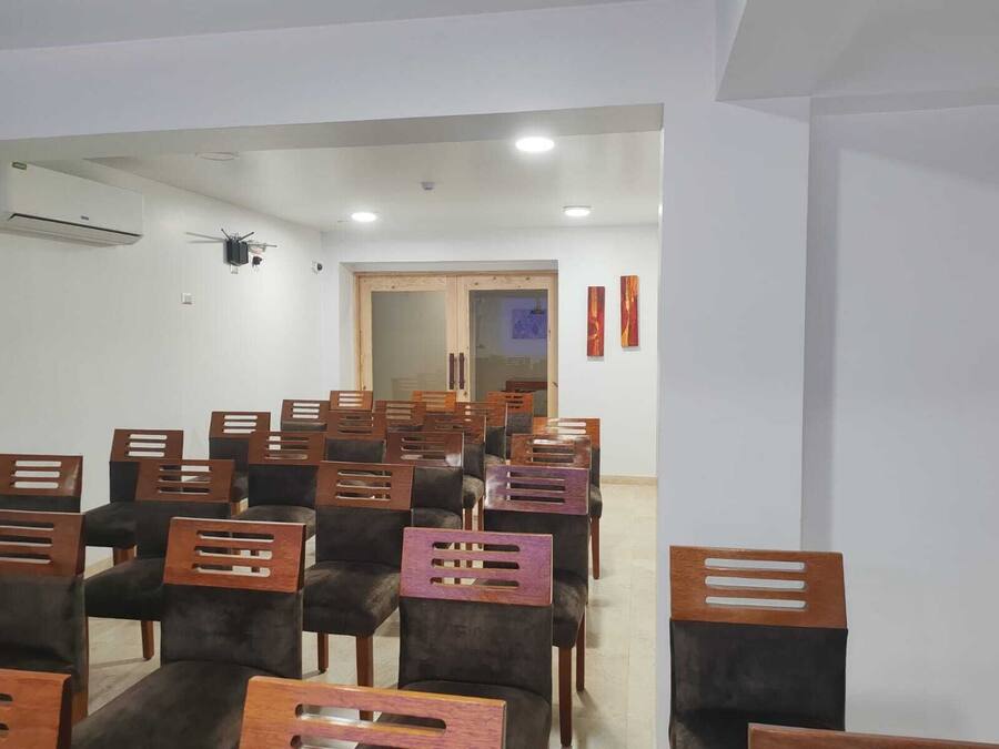 Una sala de conferències amb files de cadires, un aire condicionat i una porta que dona a una altra sala.