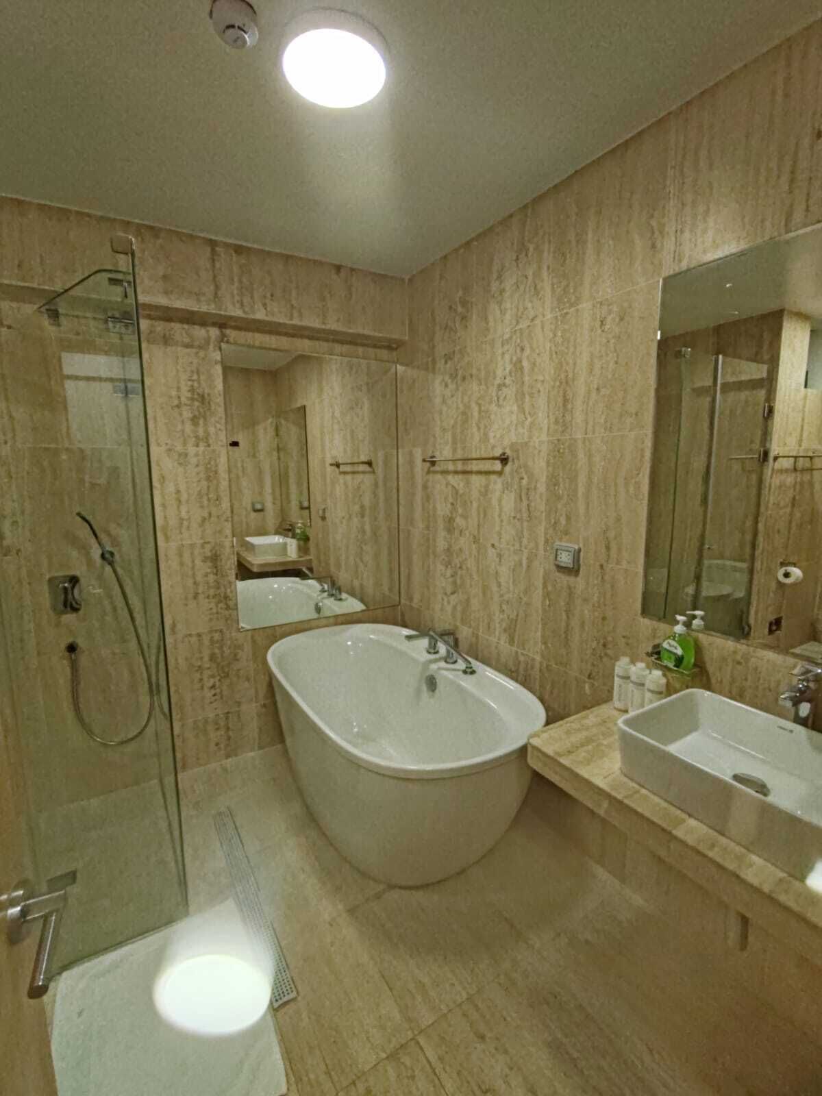 A bathroom with a glass-enclosed shower, a freestanding bathtub, and two sinks.