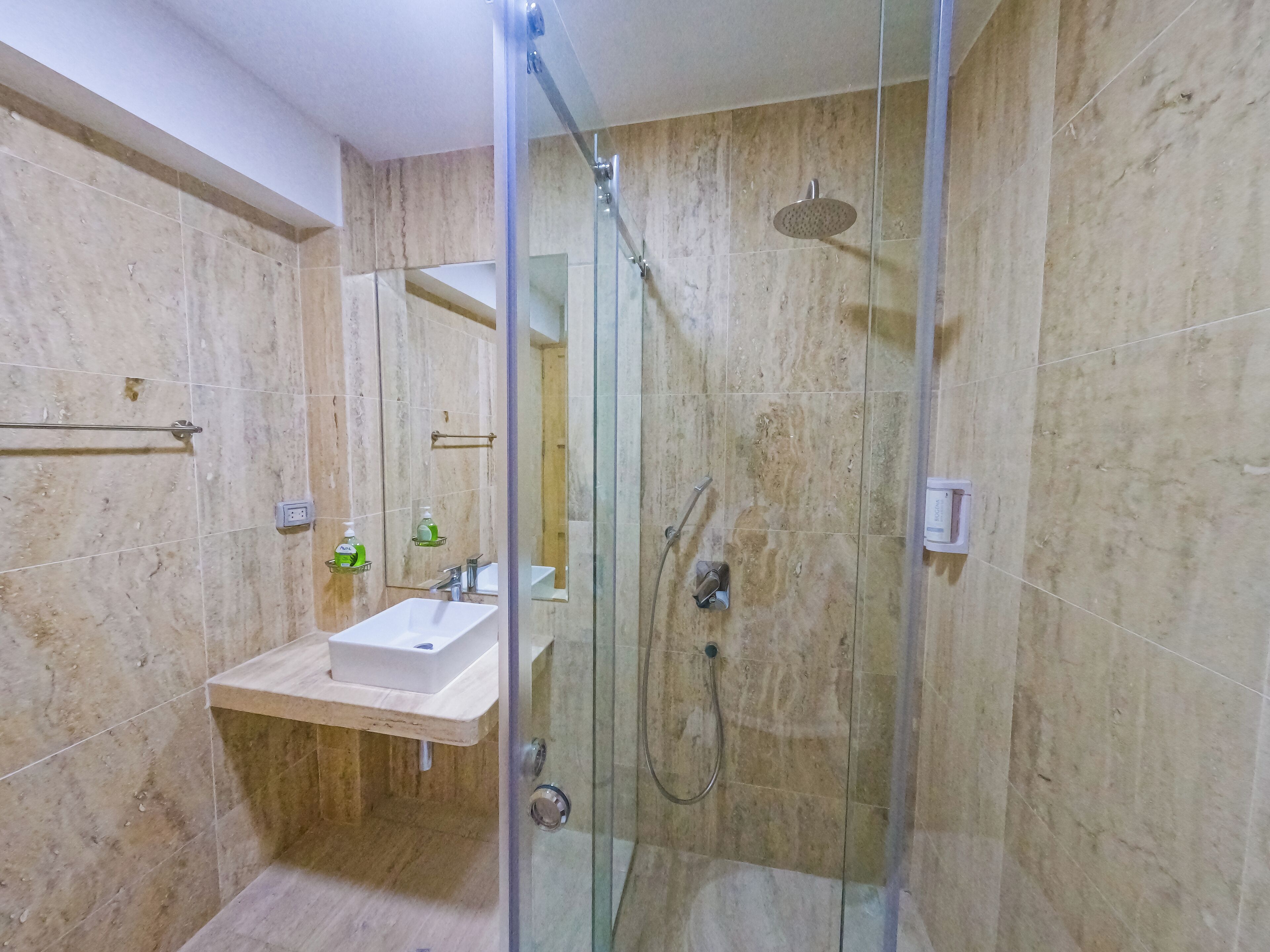 Casa de banho moderna com chuveiro de vidro, lavatório e espelho.