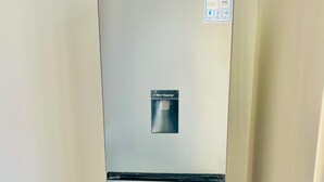 A Hisense refrigerator with a water dispenser, located in a room with tiled flooring and a plain wall.